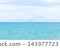 Minimalist turquoise seascape with pale sky, calm horizon, and distant island in a wide panorama 143977723