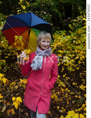 Active senior woman holding colorful umbrella smiling and enjoying autumn wellness in park. Mature female lifestyle and healthy aging Active senior woman holding colorful umbrella smiling and enjoying autumn wellness in park. Mature female lifestyle and healthy aging 143979587