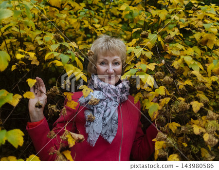 Happy senior woman in pink coat smiling outdoors in autumn park. Active elderly lifestyle, healthy aging and seasonal wellness concepts. 143980586