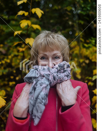 Happy senior woman in pink coat smiling outdoors in autumn park. Active elderly lifestyle, healthy aging and seasonal wellness concepts. Happy senior woman in pink coat smiling outdoors in autumn park. Active elderly lifestyle, healthy aging and seasonal wellness concepts. 143980608