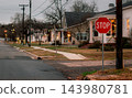 JEFFERSON, TEXAS: A red stop sign stands at a quiet street corner in a historic residential neighborhood illuminated with Christmas lights at dusk. 143980781