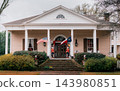 JEFFERSON, TEXAS: A grand beige Southern plantation-style historic home with white columns, grand brick steps, nutcrackers, an American flag, and a Texas flag. 143980851