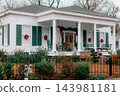 JEFFERSON, TEXAS: A classic white historic home adorned for Christmas with green shutters, red bows, wreaths, a wrought-iron fence, and holiday decorations on the front porch. 143981181