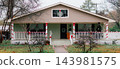 JEFFERSON, TEXAS: A single-story beige home decorated for Christmas with red and white candy cane ribbon wrapped around the porch railings and columns. 143981575