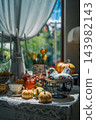 autumn harvest table setting with orange pumpkins near bright window, cozy fall indoor halloween arrangement featuring ceramic chicken candlestick 143982143