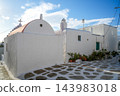 Whitewashed chapel and traditional buildings along stone-paved street in Mykonos, Greece 143983018
