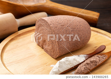raw sorghum flour dough for making homemade noodles, placed on a wooden peel with rolling pin and wooden spoons of flour. raw sorghum flour dough for making homemade noodles, placed on a wooden peel with rolling pin and wooden spoons of flour. 143988265