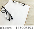 Clipboard and black-rimmed glasses - for checking documents, brainstorming ideas, business, studying, and desk work. 143996393