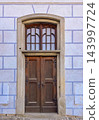 An old double wooden door set in a prominent stone archway 143997724