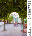 A lush green promenade features trained trees forming a living vaulted ceiling 143997731