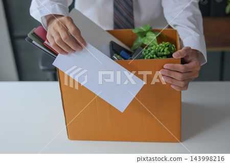 Businessman quitting job submitting resignation letter and packing personal belongings into cardboard box ready to leaving company. Businessman quitting job submitting resignation letter and packing personal belongings into cardboard box ready to leaving company. 143998216