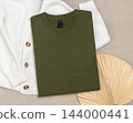 Military green folded t-shirt mockup near knitted cardigan and palm leaf, template for print on demand 144000441