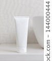 White blank cream tube mockup near white towel in beige bathroom, unbranded cosmetic packaging 144000444