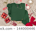 Blank dark green folded sweatshirt mockup near Christmas decor, copy space. Holiday apparel flat lay 144000446