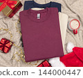 Blank dark red folded sweatshirt mockup near Christmas decor. Holiday apparel flat lay 144000447