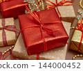 Wrapped Christmas gift boxes with red ribbon bow and gold ornaments. Holiday celebration 144000452