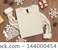 Blank beige folded sweatshirt mockup near rustic Christmas decor on wood. Holiday template 144000454