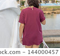 Dark red shirt mockup, young woman walking on a boat, back view with copy space. Summer lifestyle 144000457