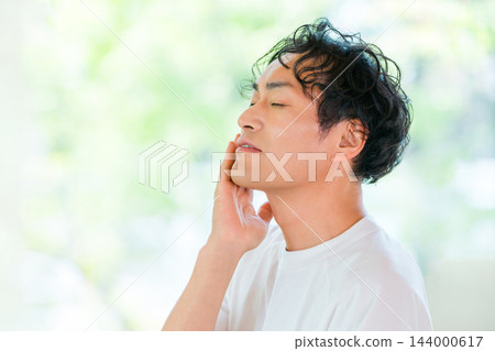 一張保養品圖片，畫面中一名男子閉著眼睛撫摸自己的臉頰。 144000617