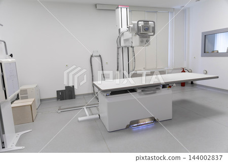 Empty modern diagnostic radiography room equipped with digital medical x-ray machine, examination table, radiological imaging column, healthcare technology setup. Empty modern diagnostic radiography room equipped with digital medical x-ray machine, examination table, radiological imaging column, healthcare technology setup. 144002837