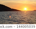 Golden sunset over Adriatic coastline with hill silhouette and pink lens flare on sea 144005039