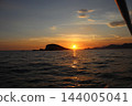 Golden sunset reflection path on Adriatic Sea with rocky island silhouette near Cavtat 144005041