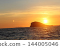 Golden Adriatic sunset with lens flare over sea and silhouette of rocky island near Cavtat 144005046