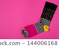 Pair of colorful patterned socks with polka dots and stripes on bright pink background, creative promo banner mockup with copy space 144006168