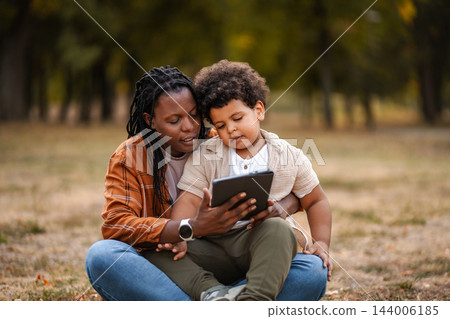 Mother and son bonding while using digital tablet outdoors 144006185