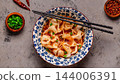 Wontons are placed in a bowl with spicy sauce. 144006391