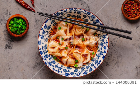 Wontons are placed in a bowl with spicy sauce. Wontons are placed in a bowl with spicy sauce. 144006391