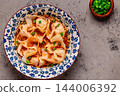 Wontons are placed in a bowl with spicy sauce. 144006392
