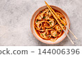 Wontons are placed in a bowl with spicy sauce. 144006396
