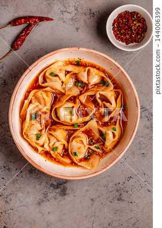 Wontons are placed in a bowl with spicy sauce. Wontons are placed in a bowl with spicy sauce. 144006399