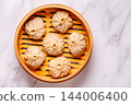 Steaming basket filled with dumplings on a marble table 144006400