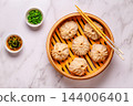 Steaming basket filled with dumplings on a marble table 144006401