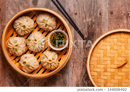 Steam basket with dumplings served with dipping sauce on a wooden table Steam basket with dumplings served with dipping sauce on a wooden table 144006402