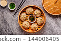 Steamed dumplings served in a bamboo basket with dipping sauce 144006405