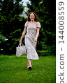 Woman with a tote bag walking through a green park 144008559