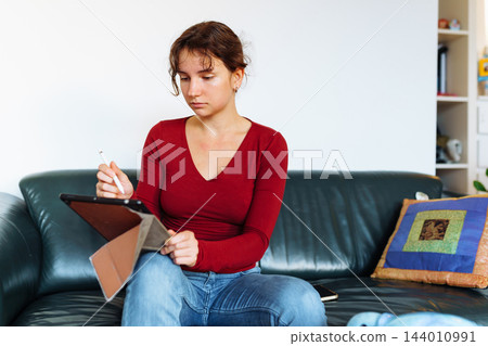 young woman using tablet while sitting on leather green sofa young woman using tablet while sitting on leather green sofa 144010991