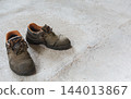 Worn work boots standing on concrete floor. 144013867