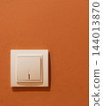 White light switch mounted on orange wall 144013870