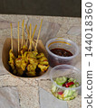 Grilled chicken satay skewer with sauce and cucumber salad in takeaway packaging 144018360