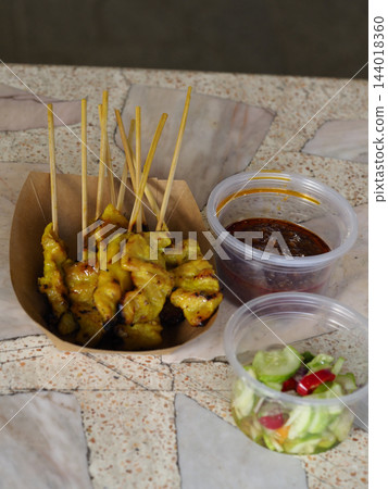 Grilled chicken satay skewer with sauce and cucumber salad in takeaway packaging Grilled chicken satay skewer with sauce and cucumber salad in takeaway packaging 144018360