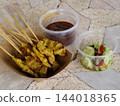Grilled chicken satay skewer with sauce served on patterned tabletop 144018365