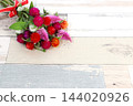一束色彩艷麗的千日紅花，背景是木紋。 144020926