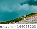 Rocky mountain slope above a turquoise alpine lake with rippled water and reflections 144023203