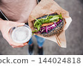 Close up of woman hands holding delicious organic salmon vegetarian burger and homebrewed IPA beer on open air beer an burger urban street food festival in Ljubljana, Slovenia 144024818