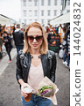 Beautiful young woman holding delicious organic salmon vegetarian burger and homebrewed IPA beer on open air beer an burger urban street food festival in Ljubljana, Slovenia 144024832