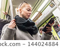 Young woman passenger using smartphone while moving in the modern metro, commuting by public transport. 144024884